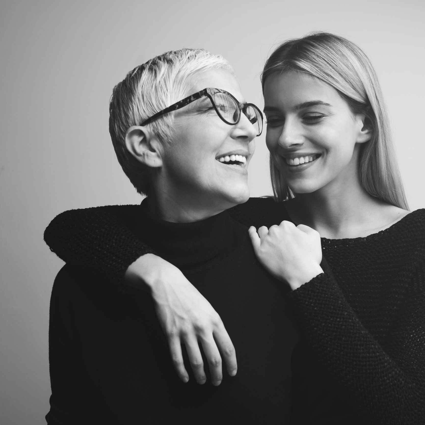 Studio shot of mother and daughter. Both of them wearing black. Black and white photo.